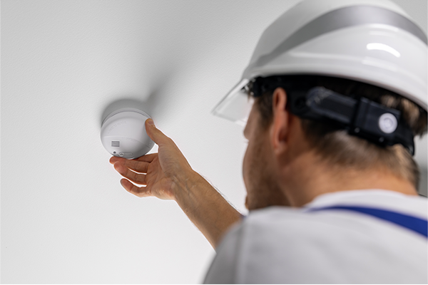 Person testing a smoke detector